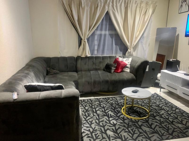 A living room space featuring tiled flooring and a window with curtains.