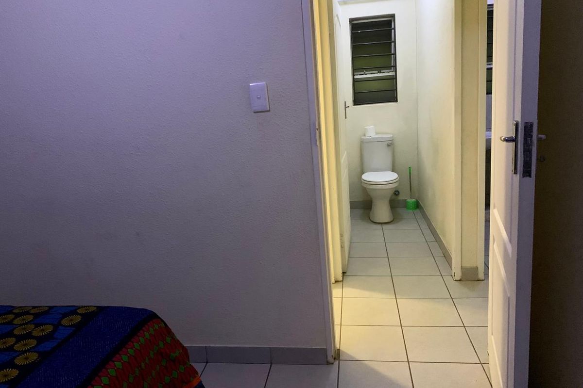 A functional bathroom featuring tiled flooring and a standard toilet, accessible directly from the adjacent bedroom area.