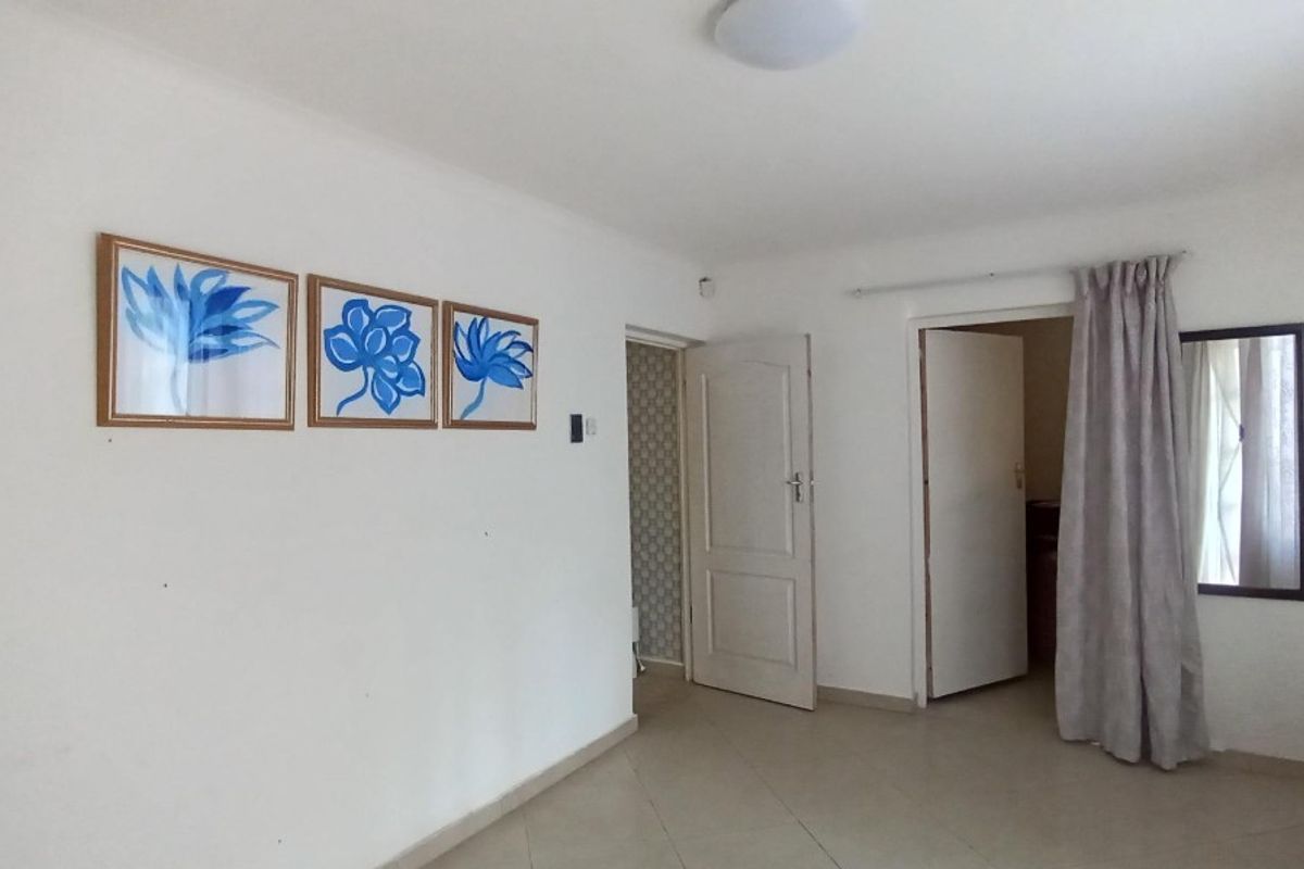A neutral living area featuring tiled flooring, multiple doorways, and simple interior finishes, providing a versatile space for customization.
