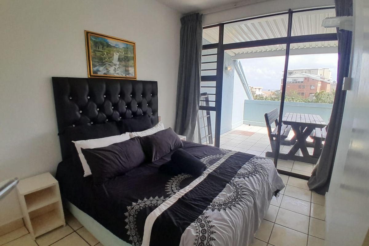 A bedroom featuring tiled flooring and large sliding glass doors that open onto a private balcony, providing natural light and outdoor access.
