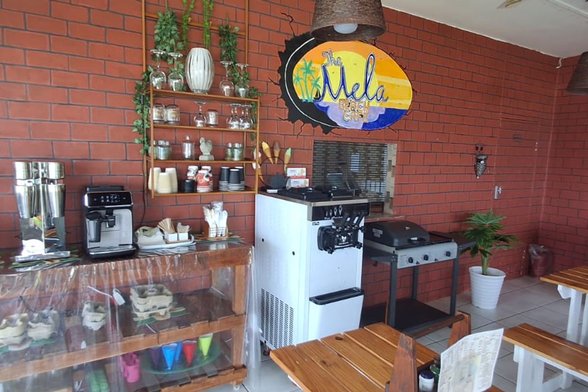 A commercial cafe space featuring exposed red brick walls, tiled flooring, and built-in service counters suitable for food and beverage preparation.