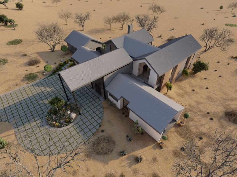 Aerial view of a modern architectural house design featuring a metal roof, stone accents, and a circular paved driveway in a desert landscape.
