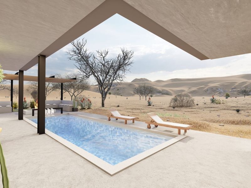 A modern outdoor pool area featuring a rectangular swimming pool, covered patio space, and expansive desert landscape views.