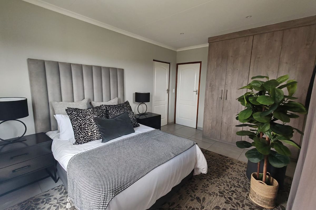 A well-maintained bedroom featuring built-in wooden cupboards, neutral wall finishes, and tiled flooring, offering a clean and functional living space.