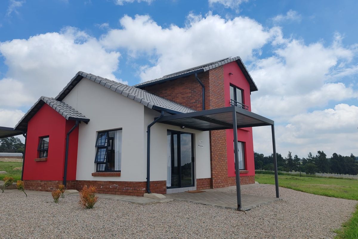 A modern double-story house featuring a combination of red brick and painted plaster exterior walls, a tiled roof, and a covered patio area.