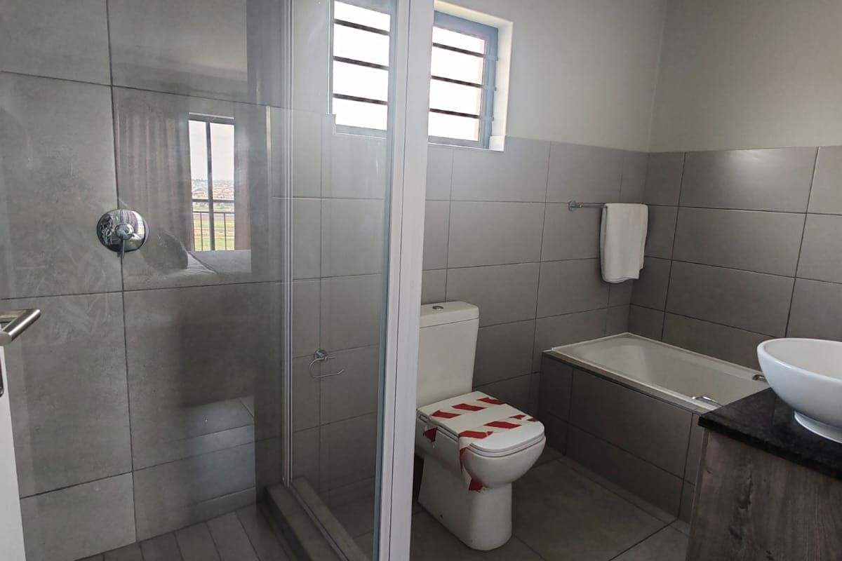 Modern bathroom featuring a glass-enclosed shower, a built-in bathtub, a vanity with a countertop basin, and a toilet.