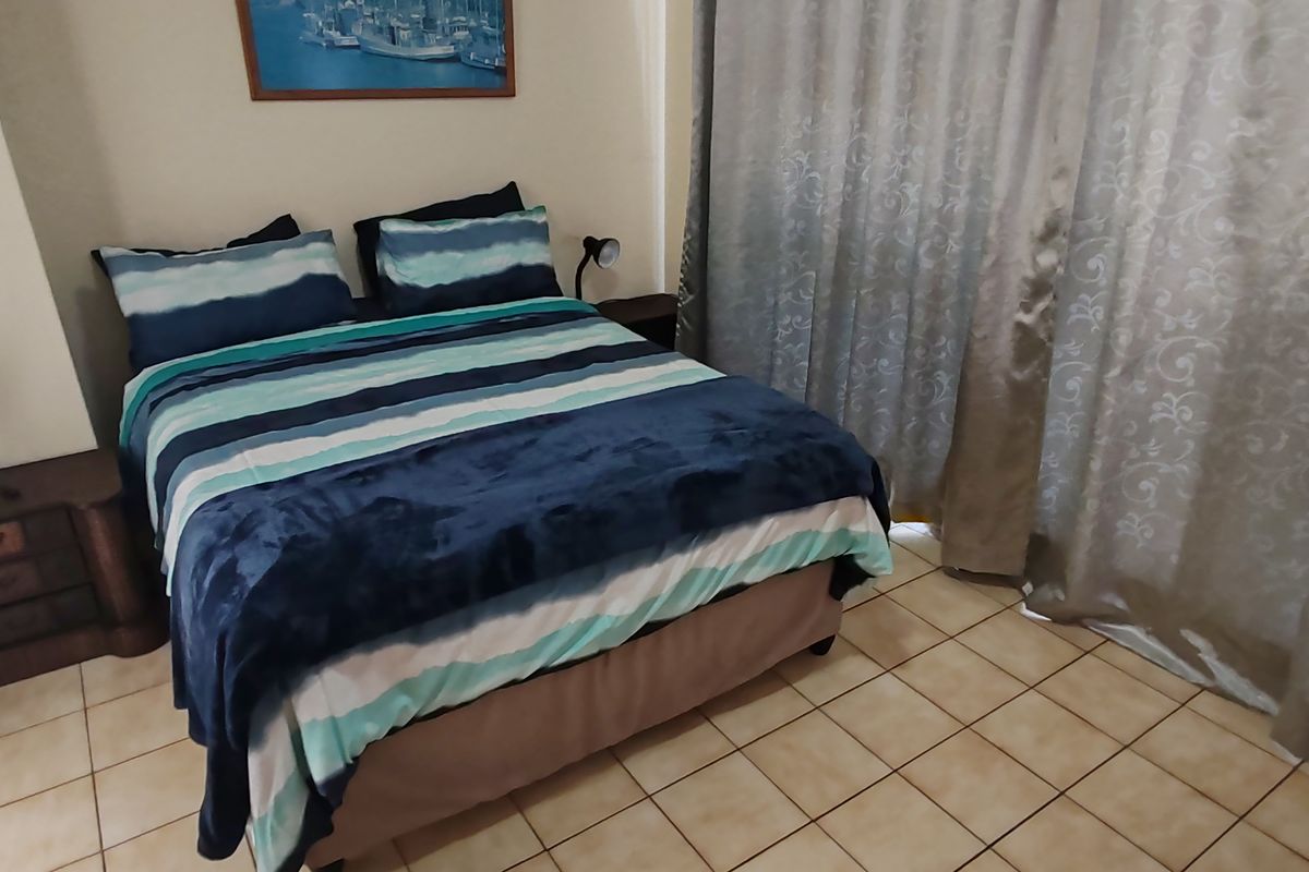 A bedroom featuring tiled flooring and floor-to-ceiling curtains, providing a functional and neutral space.