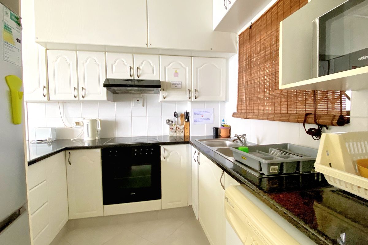 A functional kitchen featuring white cabinetry, dark granite countertops, a built-in oven, extractor fan, and a double-basin sink.