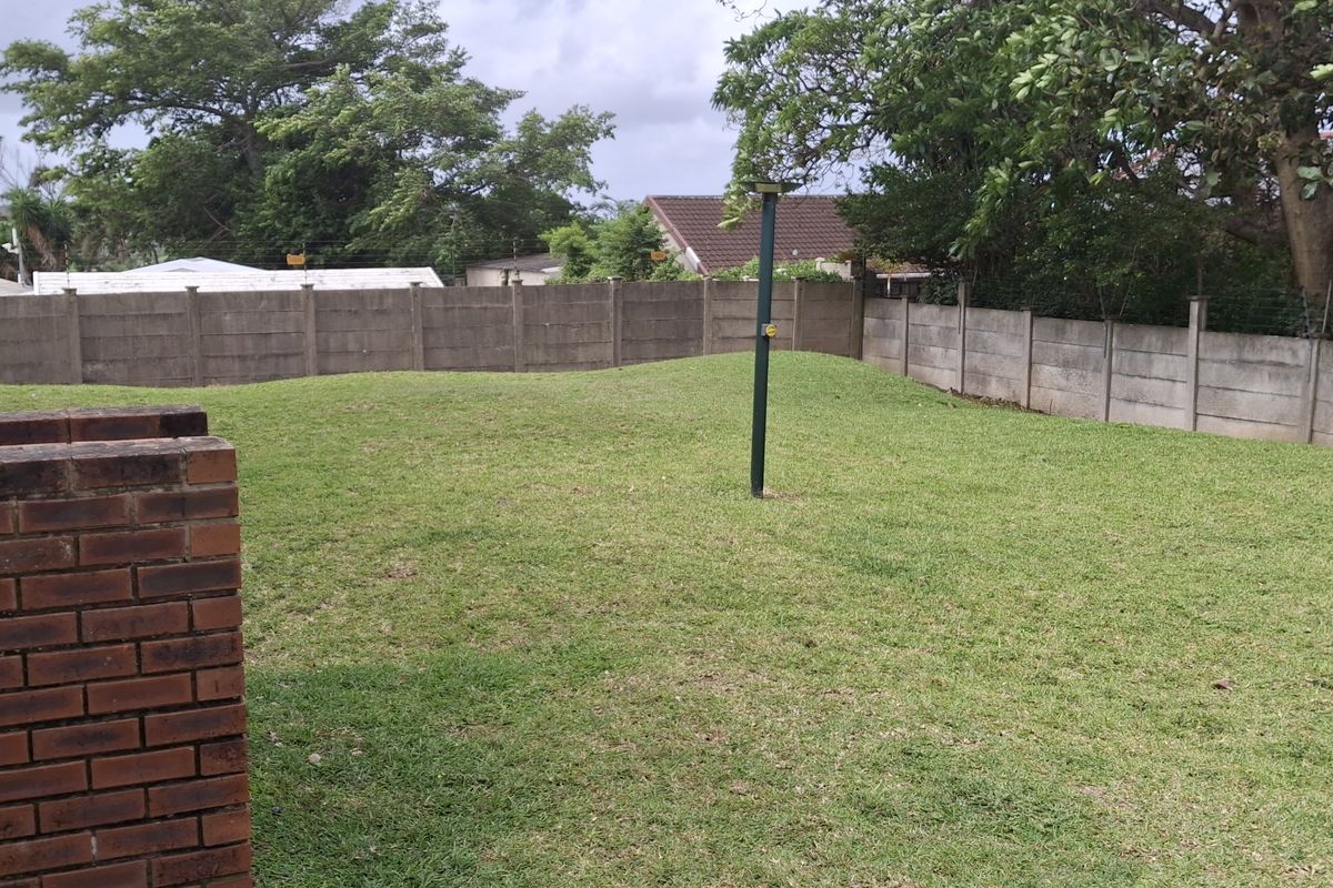 A private rear garden featuring a brick-built braai area, established lawn, and perimeter concrete walling, offering a functional outdoor space.