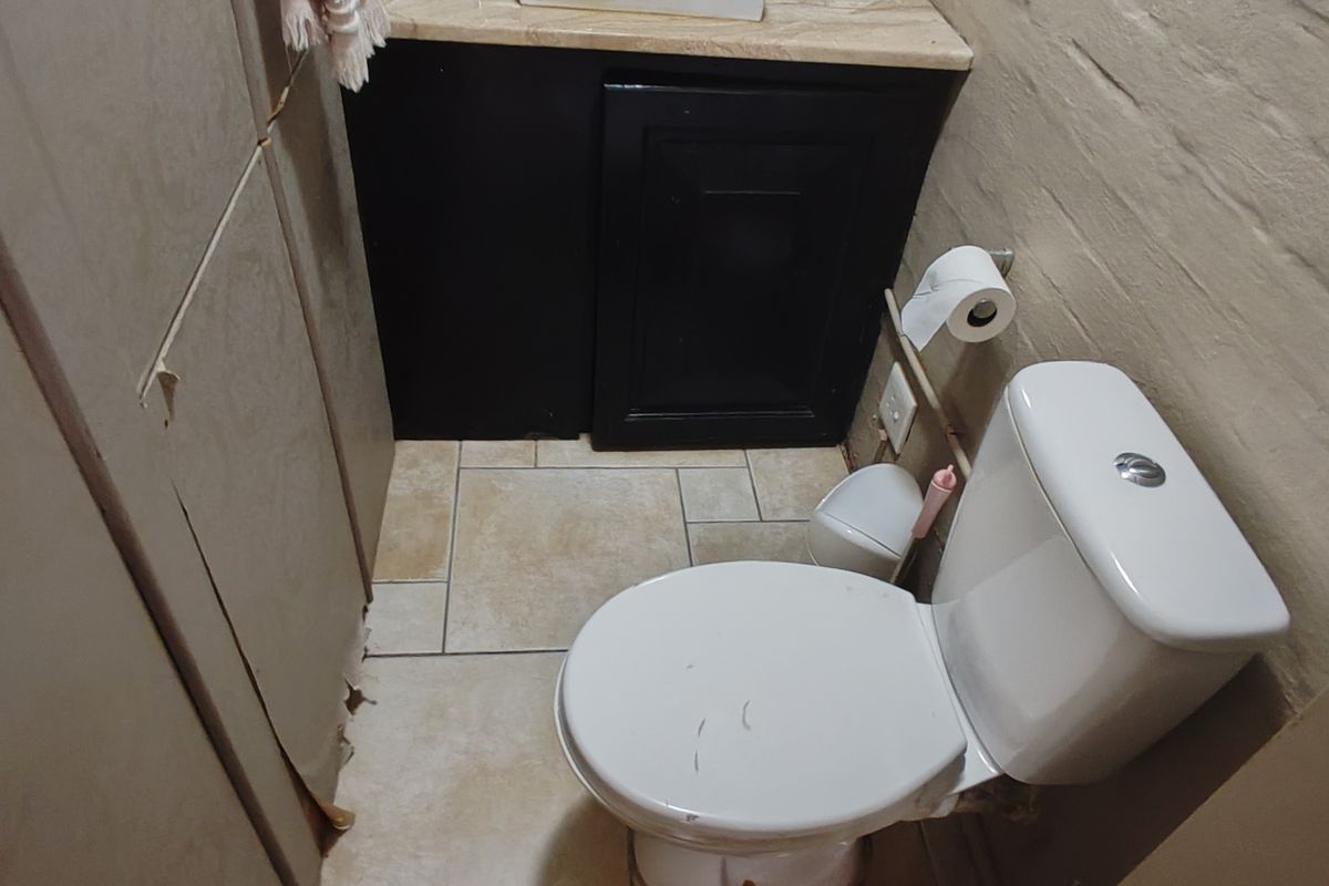 A compact guest bathroom featuring a vanity cabinet with stone countertop and a standard toilet.