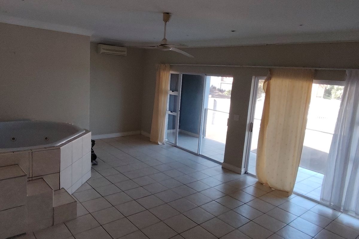 Spacious bedroom featuring a built-in corner spa bath, tiled flooring, and large sliding glass doors providing access to an outdoor area.