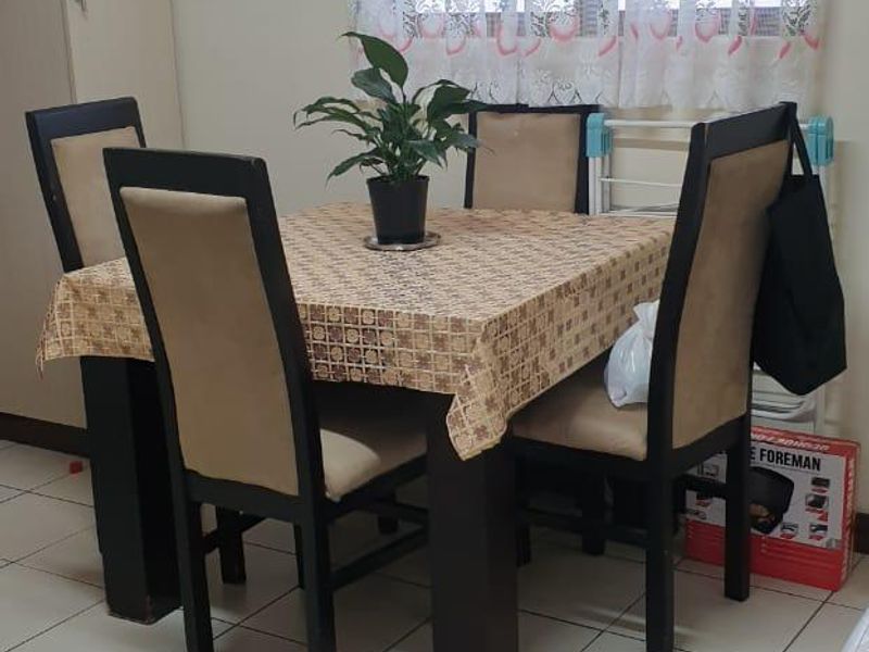 A functional dining area featuring neutral tiled flooring and a built-in storage cupboard, providing a practical space for meals.