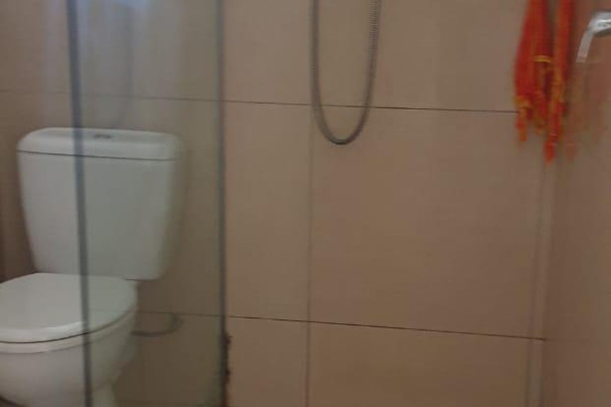 A functional bathroom featuring a glass-enclosed shower, wall-mounted shower fixtures, and tiled finishes throughout.