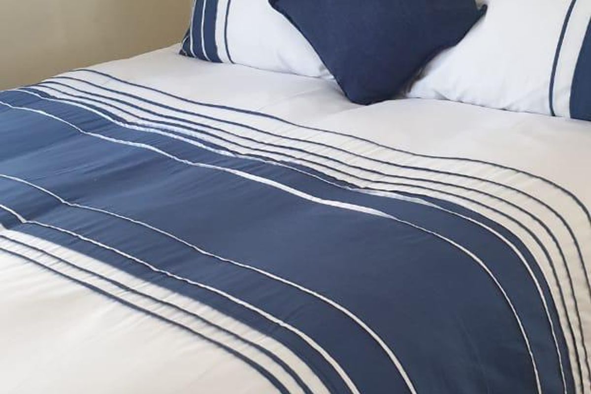 A well-maintained bedroom featuring light-toned laminate flooring and a neutral wall finish.