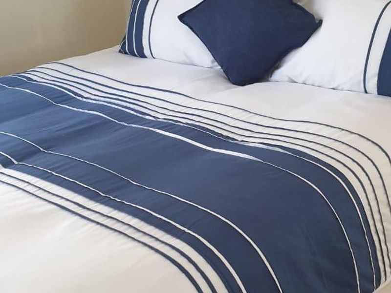 A well-maintained bedroom featuring light-toned laminate flooring and a neutral wall finish.
