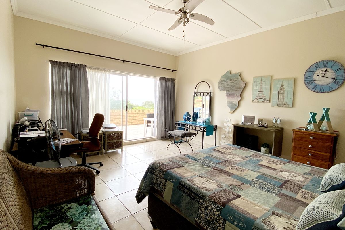 Spacious bedroom featuring tiled flooring, a ceiling fan, and large sliding glass doors providing direct access to an outdoor balcony area.