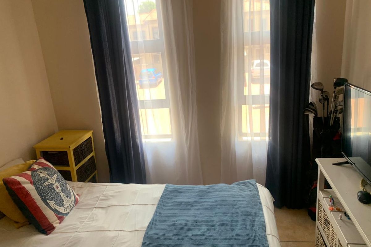 A bedroom featuring dual windows with aluminium frames, providing natural light and a view of the exterior.