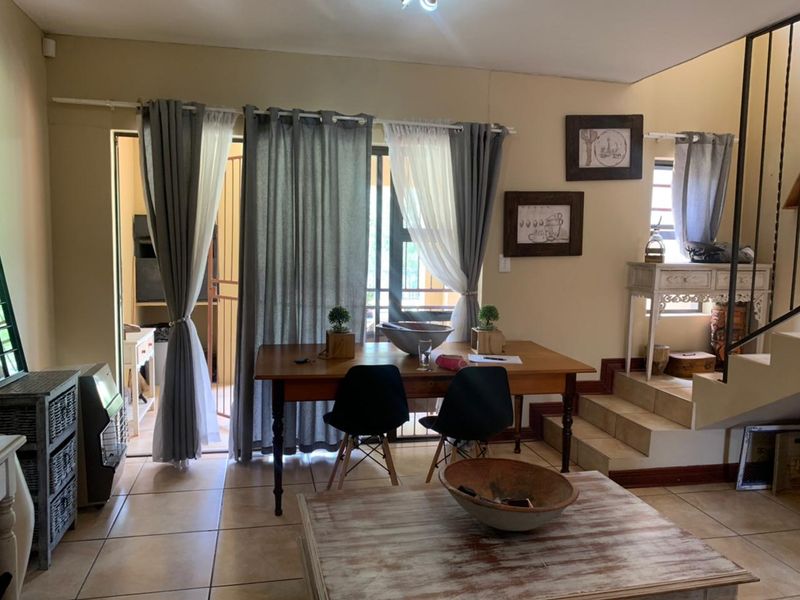 Open plan living and dining area featuring tiled flooring, a staircase, and access to an outdoor patio through a sliding glass door.