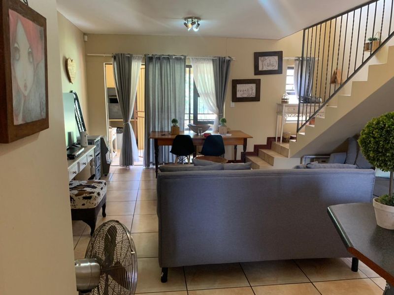Open plan living and dining area featuring tiled flooring, a staircase with a metal balustrade, and direct access to an outdoor patio area.
