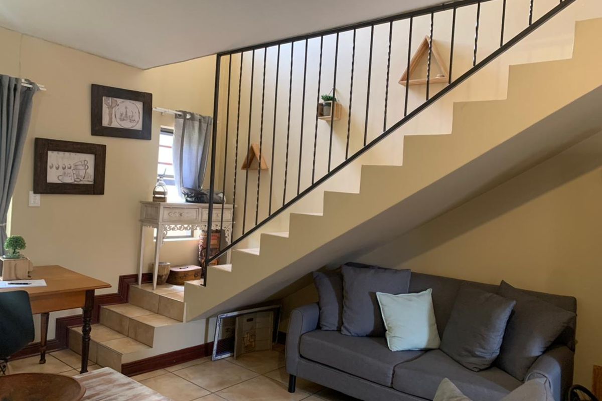 A living area featuring a staircase with a wrought iron balustrade and tiled flooring, providing a functional space under the stairs.