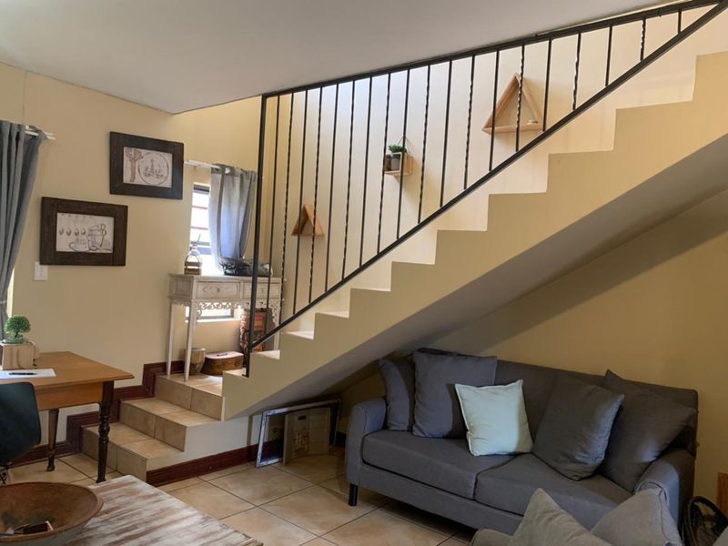 A living area featuring a staircase with a wrought iron balustrade and tiled flooring, providing a functional space under the stairs.