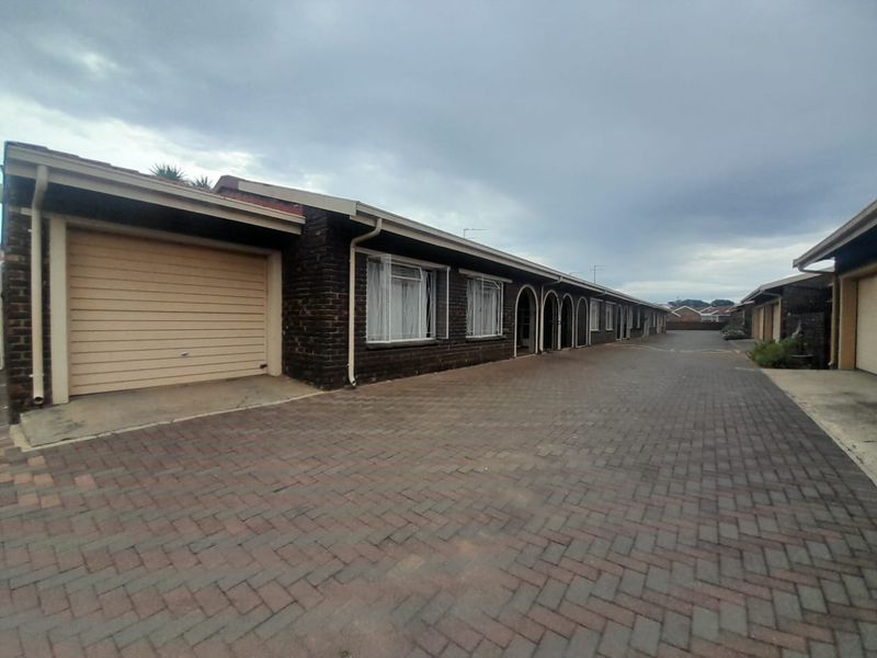 Exterior view of a townhouse complex featuring a paved driveway, brick facade, and integrated garage access.