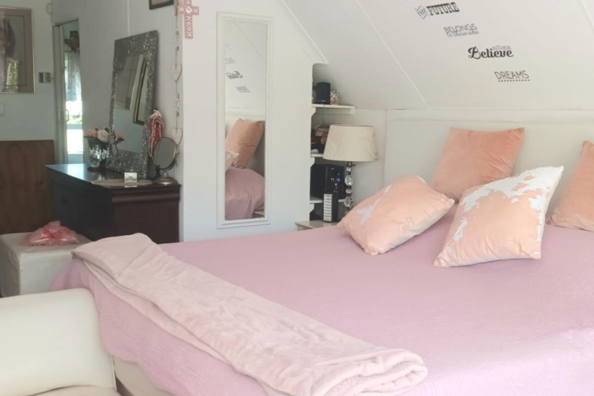 A bedroom featuring a sloped ceiling, built-in shelving, and a mirror, providing a cozy and functional living space.