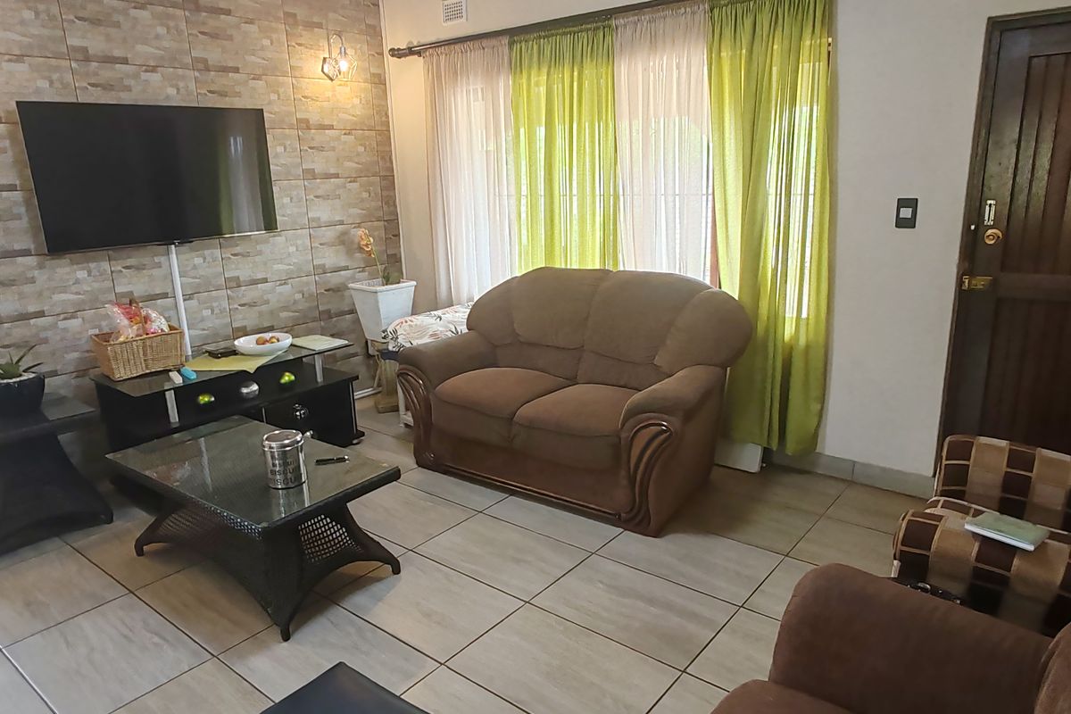 A living room featuring tiled flooring and a stone-cladding feature wall.