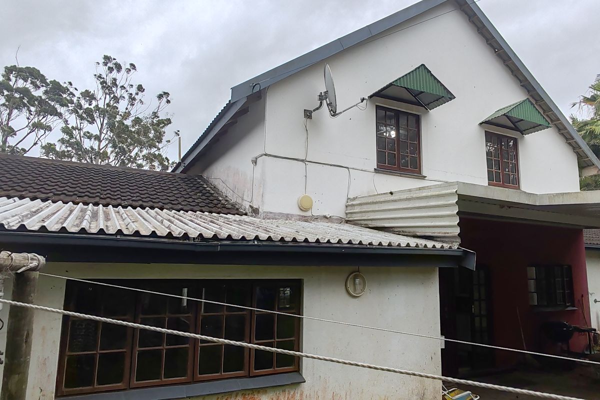 Rear exterior view of the house featuring a pitched roof, timber-framed windows, and an attached carport structure.