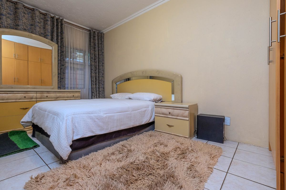 A bedroom featuring tiled flooring, built-in cabinetry, and a window with curtain treatments.
