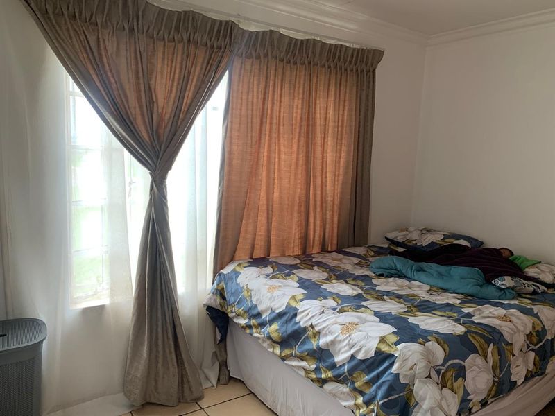 A bedroom featuring tiled flooring and a window with curtains.