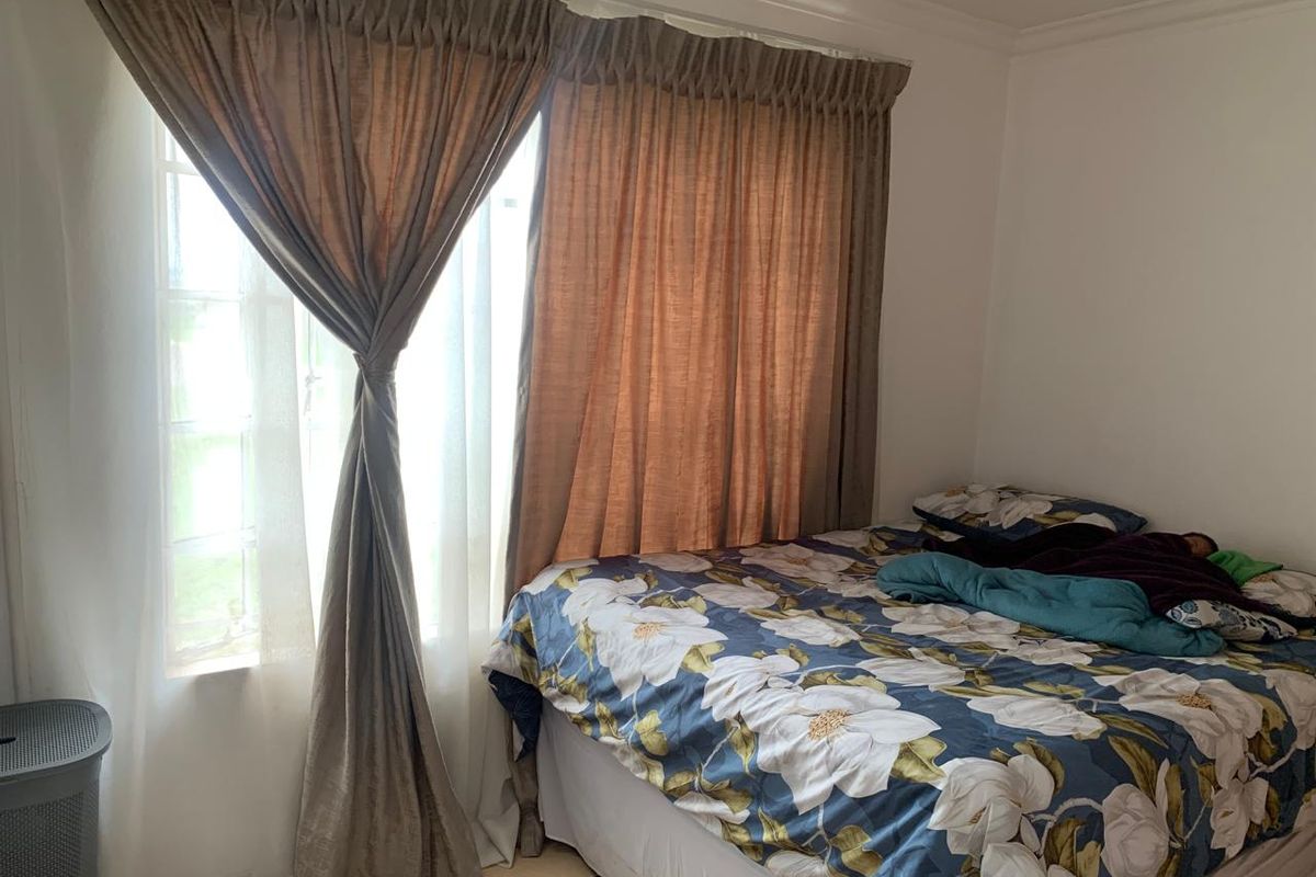 A bedroom featuring tiled flooring and a window with curtains.
