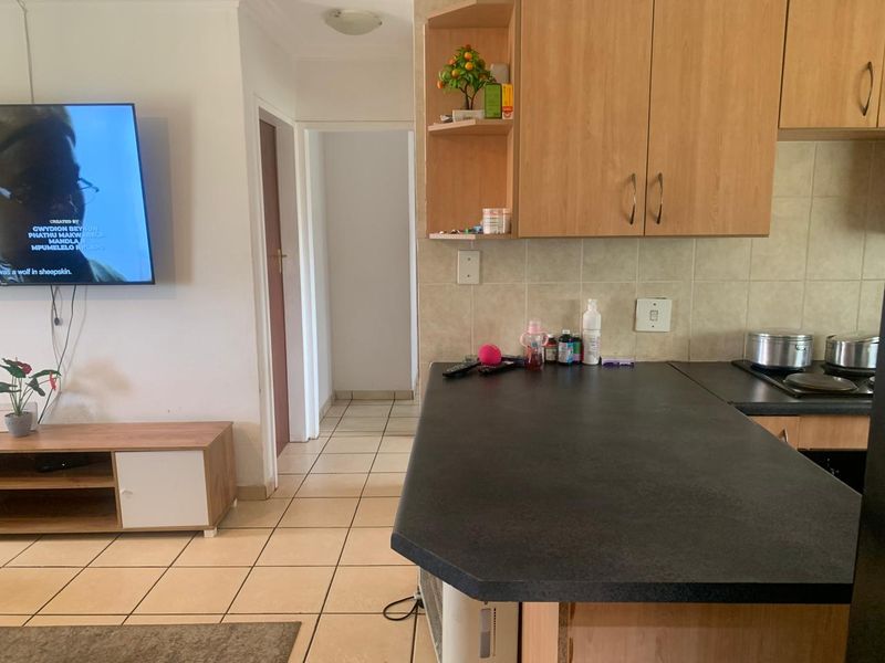 Open plan living area featuring a kitchen with laminate cabinetry, dark countertops, and tiled flooring, seamlessly connecting to the adjacent living space.
