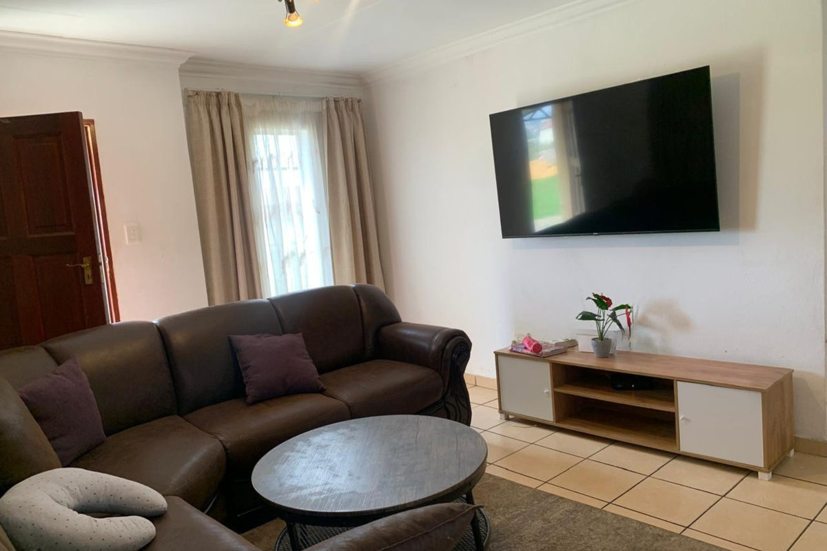 A living room featuring tiled flooring, coved ceiling cornices, and a ceiling-mounted spotlight fixture.
