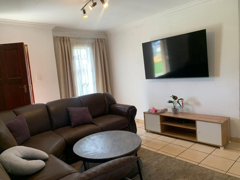 A living room featuring tiled flooring, coved ceiling cornices, and a ceiling-mounted spotlight fixture.