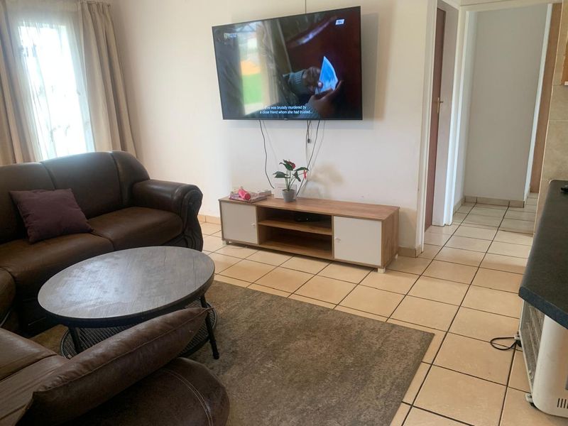A living room area featuring tiled flooring and access to internal hallways.