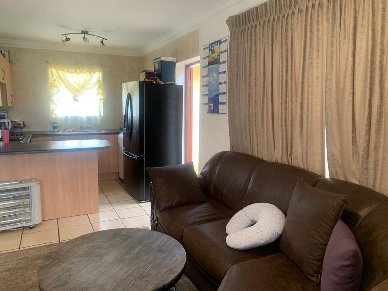 Open plan living area featuring a functional kitchen with laminate countertops and tiled flooring, seamlessly connected to the lounge space.