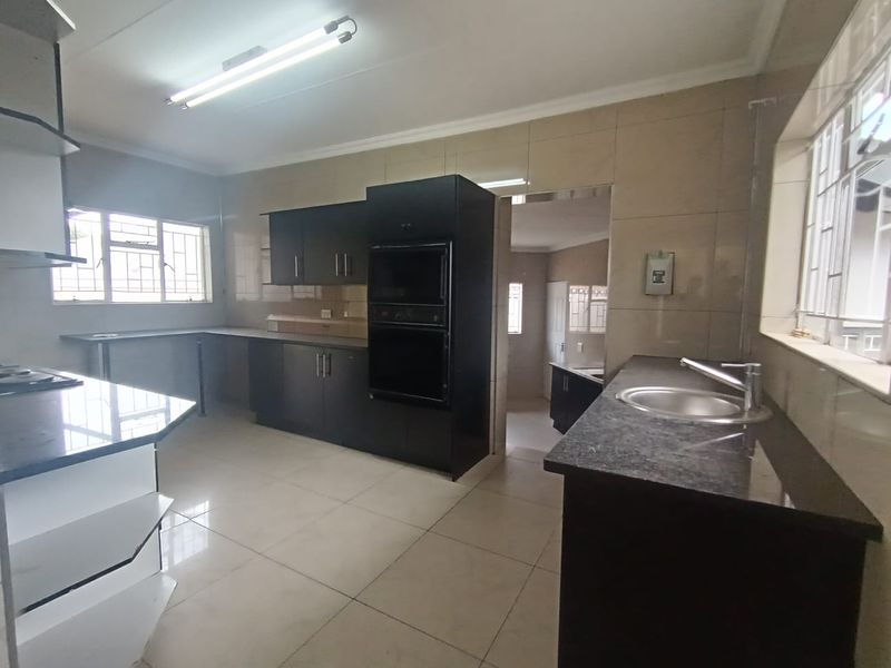 Spacious kitchen featuring dark cabinetry, granite countertops, built-in oven and microwave, tiled walls, and ample workspace.
