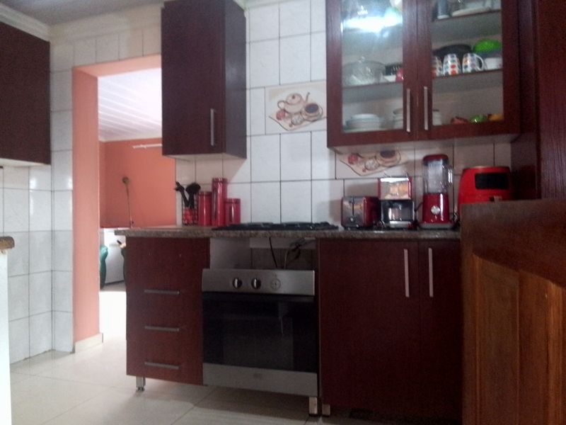 A functional kitchen featuring dark wood cabinetry, granite countertops, a built-in oven, and a gas hob with tiled splashbacks.