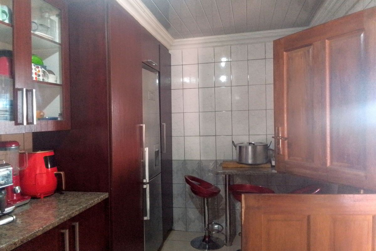A compact kitchen featuring dark wood cabinetry, granite countertops, and a tiled splashback with a tongue and groove ceiling finish.