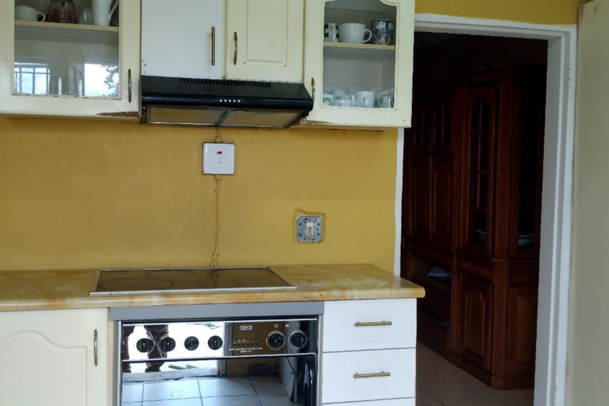 A dated kitchen featuring built-in cabinetry, an electric hob, and an oven, requiring cosmetic updates and electrical repairs.