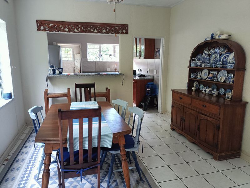 Dining room featuring tiled flooring, a decorative pass-through window with a granite breakfast bar, and access to the adjacent kitchen area.