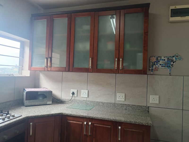 A functional kitchen featuring wooden cabinetry, granite countertops, a tiled backsplash, and built-in cooking appliances.