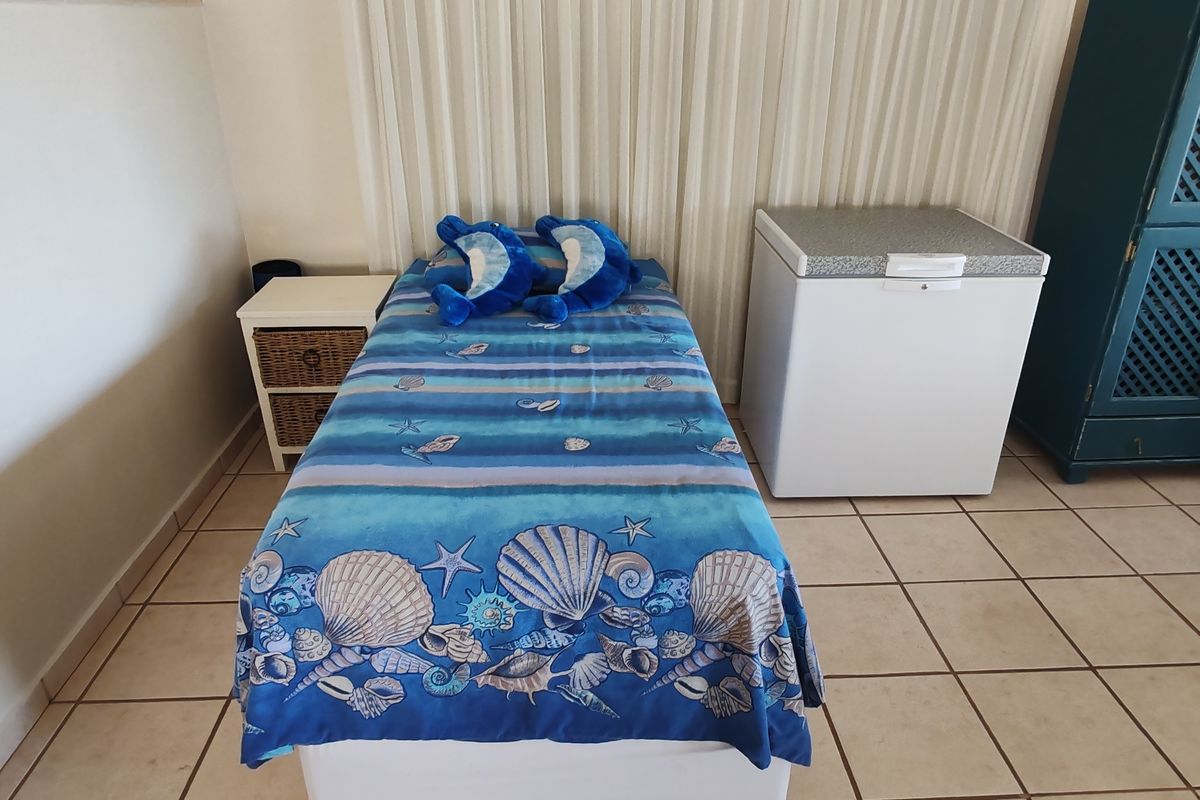 A bedroom featuring tiled flooring and vertical blinds, currently utilized with a single bed and additional storage units.