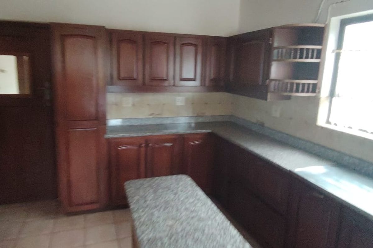 A functional kitchen featuring dark wood cabinetry, granite countertops, and a tiled floor, offering a classic layout with ample storage space.