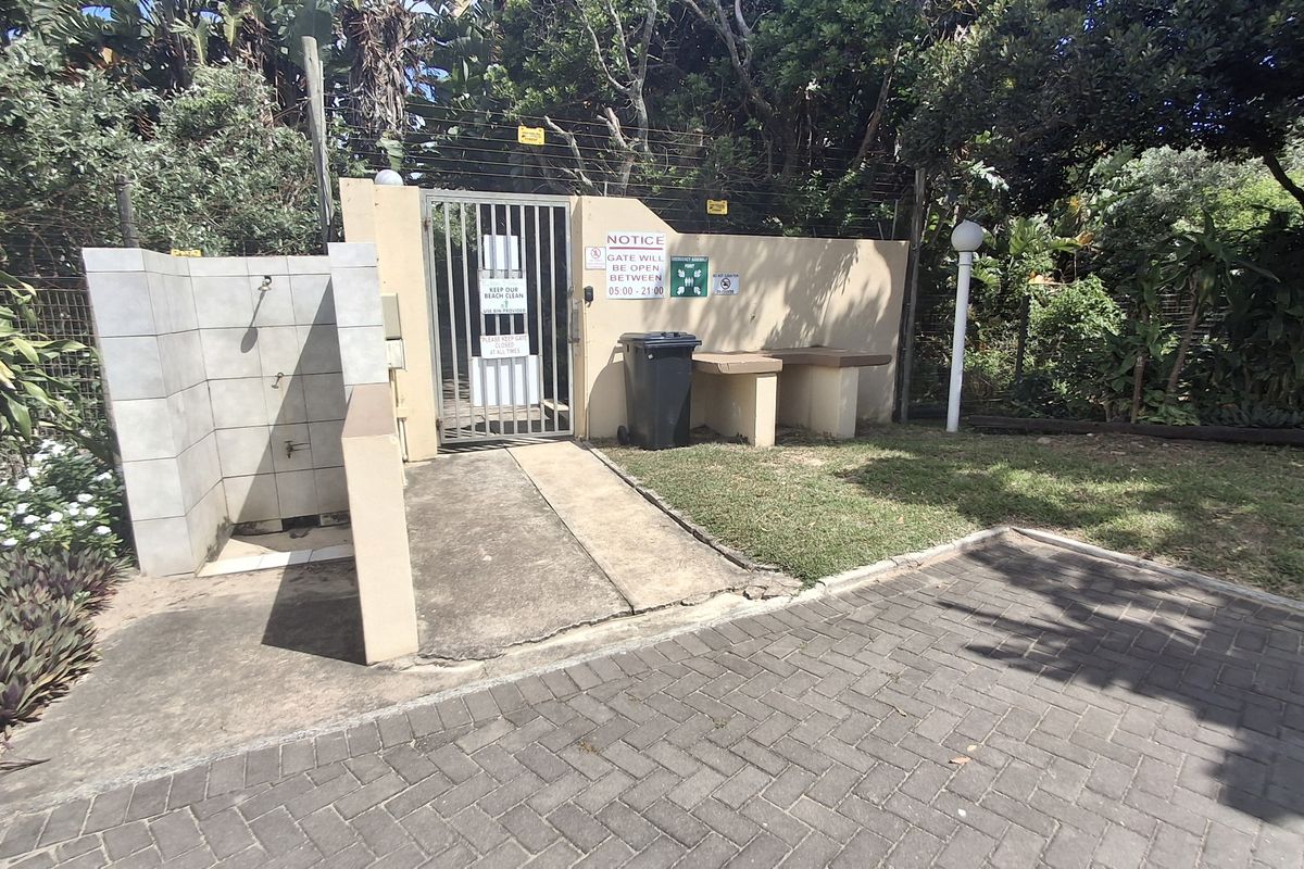 Outdoor communal area featuring a paved access path, security gate, and an external shower facility for residents.