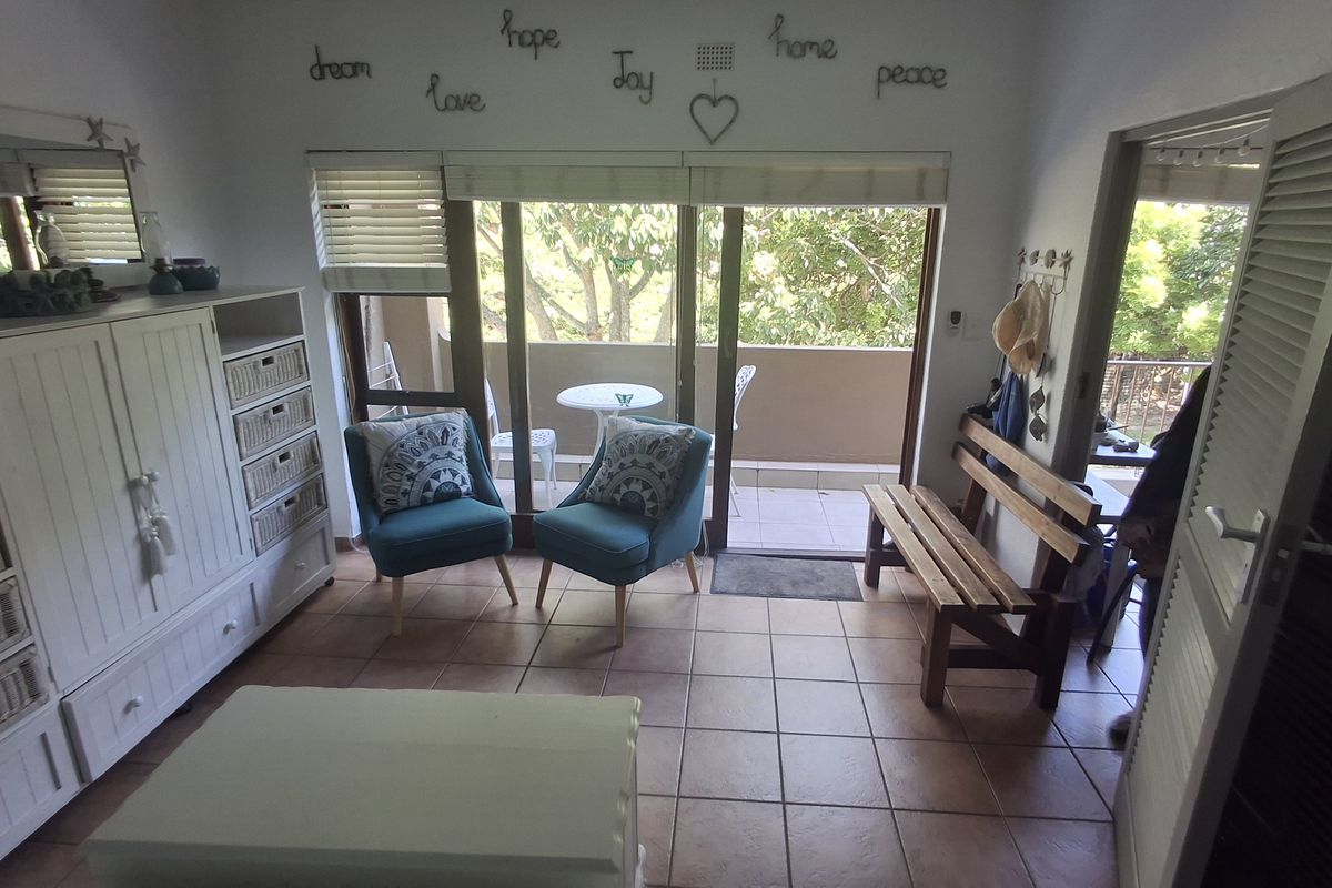 A bright living area featuring tiled flooring and large sliding glass doors that open onto a private balcony.