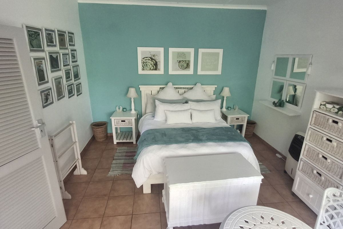 A cozy bedroom featuring tiled flooring and a prominent teal accent wall, providing a bright and inviting atmosphere.