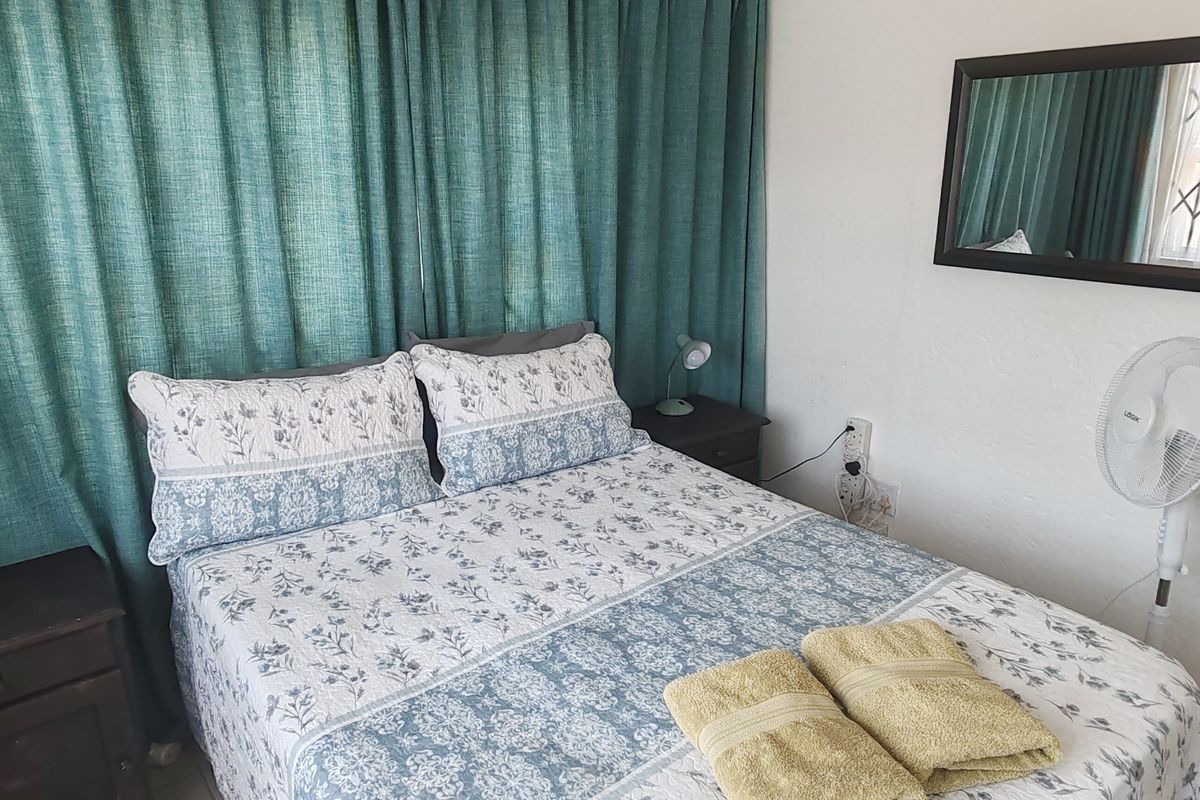 A functional bedroom featuring a window with security gate and neutral wall finishes, providing a comfortable and practical sleeping space.