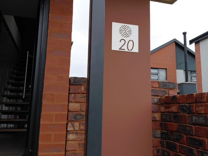 Front entrance area featuring a modern brick facade, steel structural column, and a clear house number display.